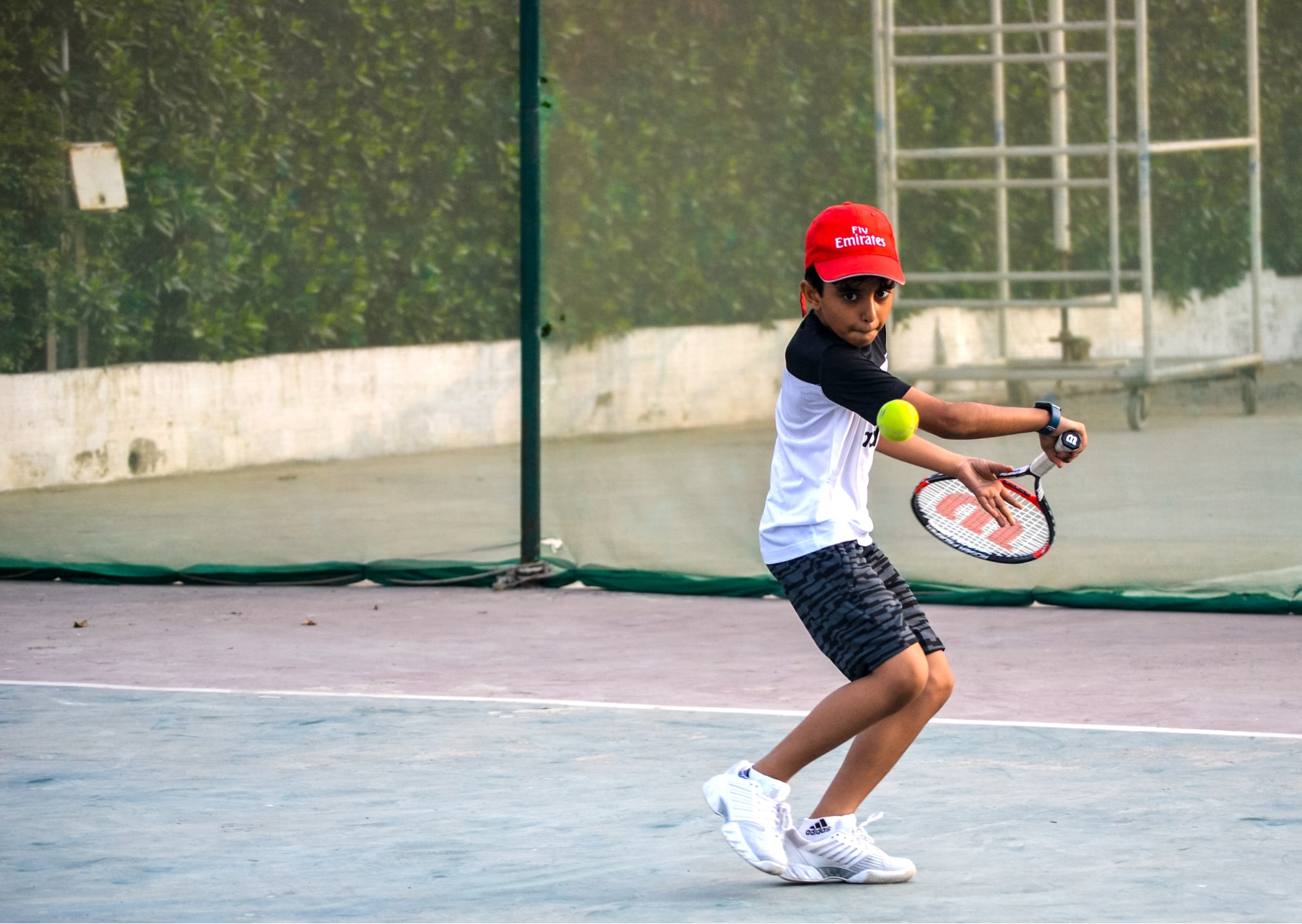 Kid in red cap playing tennis at Shamsi Tennis Academy | Ticketwala.pk